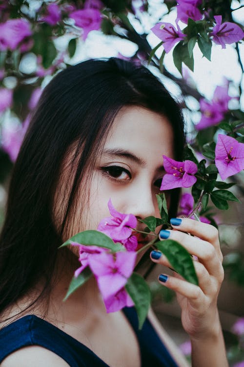 女人拿着紫色的花瓣 · 免费素材图片