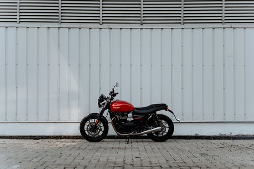 红色和黑色的摩托车停在白墙旁边 · 免费素材图片