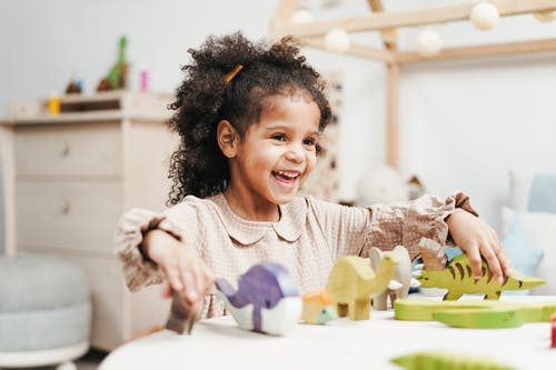 笑的女孩玩木制玩具在白色桌子上的选择性焦点照片 · 免费素材图片