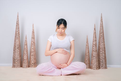 女人坐在地板上显示她的婴儿撞 · 免费素材图片