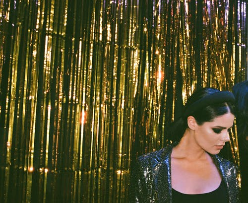 站在金箔窗帘旁边的女人 · 免费素材图片