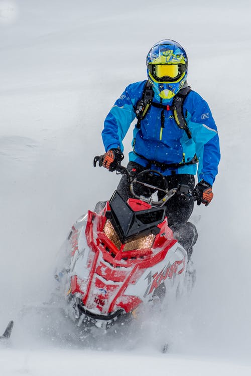 穿着蓝色夹克和头盔的男人骑红雪移动 · 免费素材图片