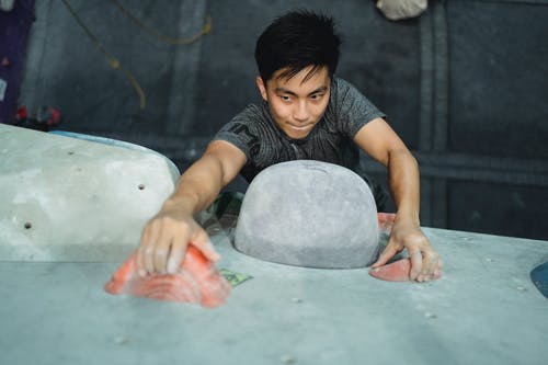 坚强的亚洲人攀岩墙在健身房 · 免费素材图片
