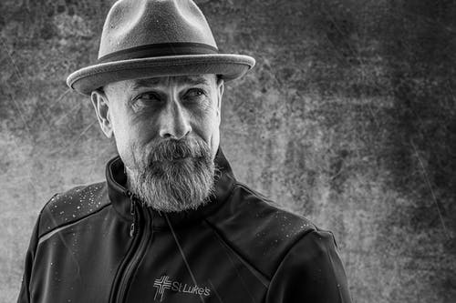 戴着黑色拉链外套和帽子的男子的灰度照片 · 免费素材图片