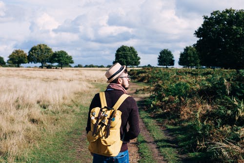 背包的人在白天在田间小径上行走 · 免费素材图片