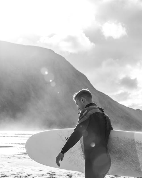 男子手持冲浪板的单色照片 · 免费素材图片