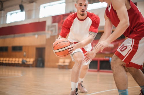 穿红色和白色耐克圆领t恤和白色短裤举行篮球的男人 · 免费素材图片