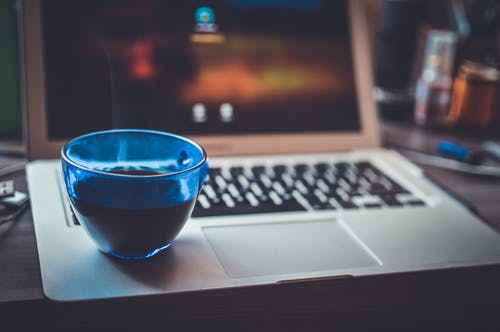 银便携式计算机上的蓝色玻璃杯 · 免费素材图片