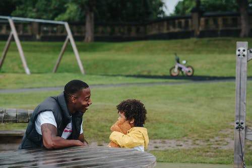 快乐的黑人儿子和父亲坐在公园 · 免费素材图片