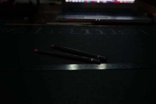 黑色铅笔在灰色钢直尺附近 · 免费素材图片