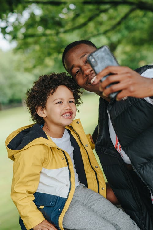 有儿子的满意的黑人采取在智能手机的自画象 · 免费素材图片