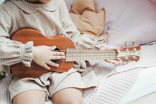 一个女孩抱着棕色的夏威夷四弦琴 · 免费素材图片