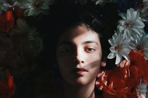 女人躺在花上的选择性焦点摄影 · 免费素材图片
