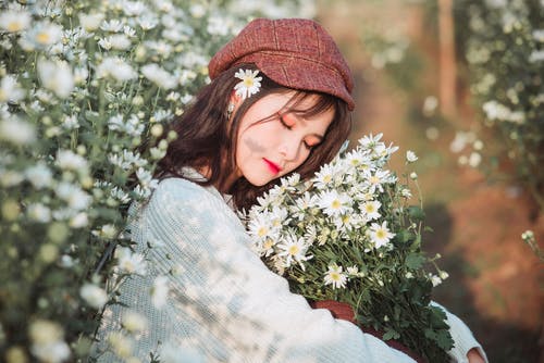 女人坐下来背着束白花 · 免费素材图片