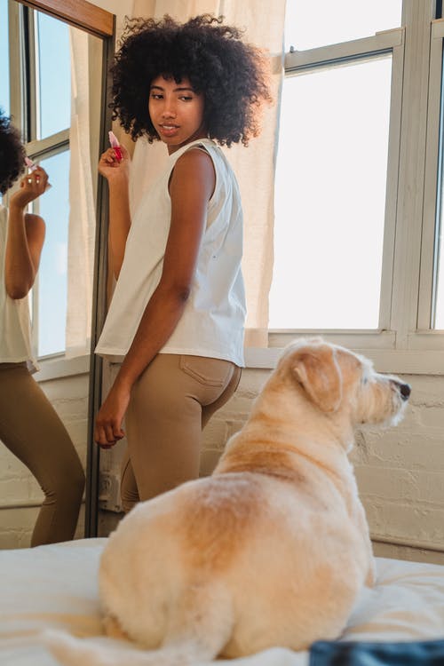黑人妇女站在镜子旁边，看着可爱的狗 · 免费素材图片