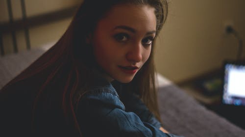 在打开的笔记本电脑附近的灰色床上的女人的选择性聚焦摄影 · 免费素材图片