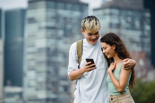 显示智能手机的快乐的亚裔人给迷人的女朋友在镇 · 免费素材图片