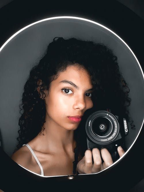 女人拿着黑色的佳能单反相机 · 免费素材图片