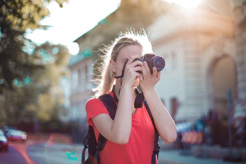 穿着红色衬衫的女人使用单反相机拍照 · 免费素材图片