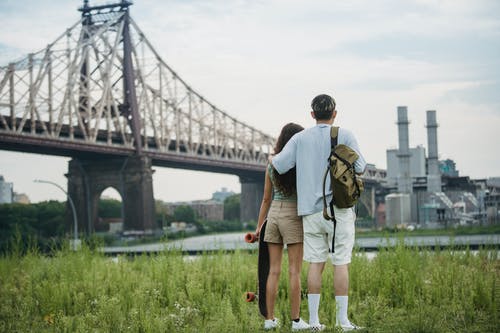 匿名浪漫情侣站在桥附近，享受城市景观 · 免费素材图片