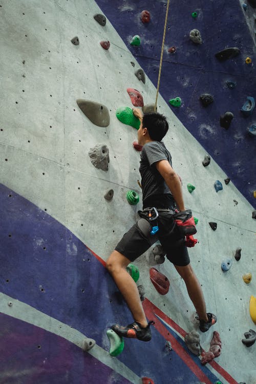 自信的登山者上升墙在健身房 · 免费素材图片