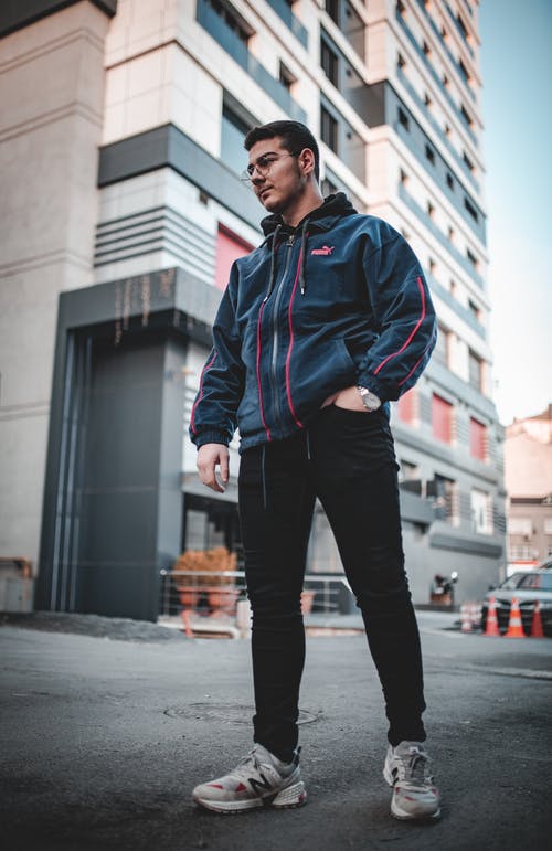 蓝色拉链夹克和黑色的裤子，站在人行道上的人 · 免费素材图片