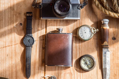 Lomo相机手表刀和able怀表附近的棕色酒瓶 · 免费素材图片