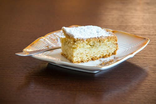 白色和棕色陶瓷板上的棕色和白色切片的蛋糕 · 免费素材图片