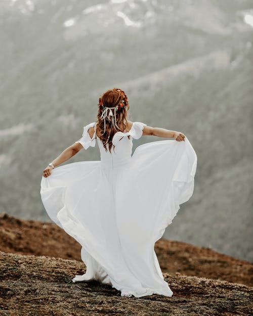 女人站在褐色的田野上的白色连衣裙的背影照片 · 免费素材图片