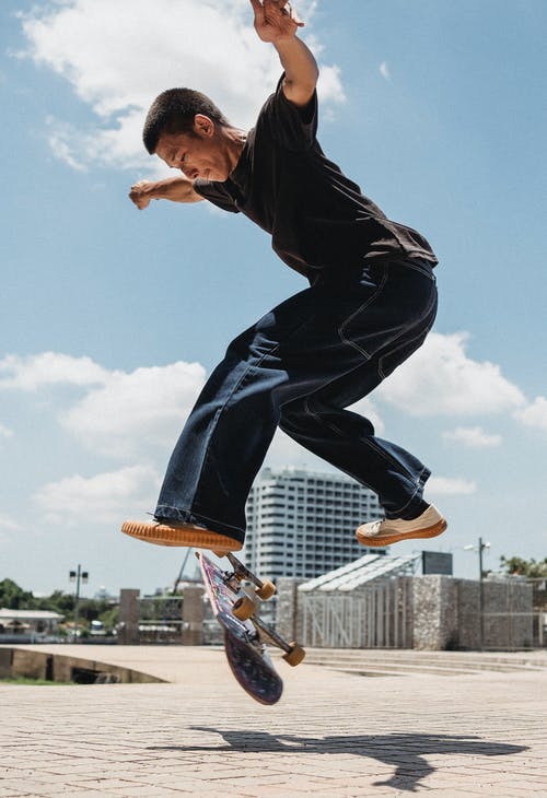 跳上滑板在公园里的年轻溜冰者 · 免费素材图片