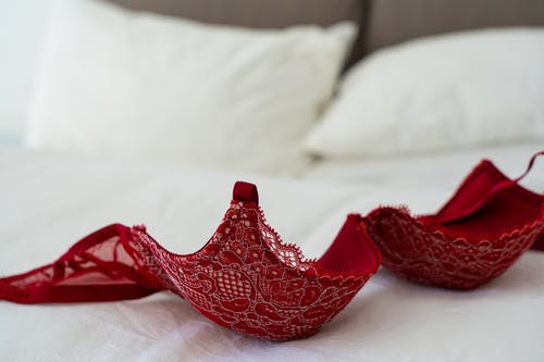 白色床上的红色蕾丝胸罩 · 免费素材图片