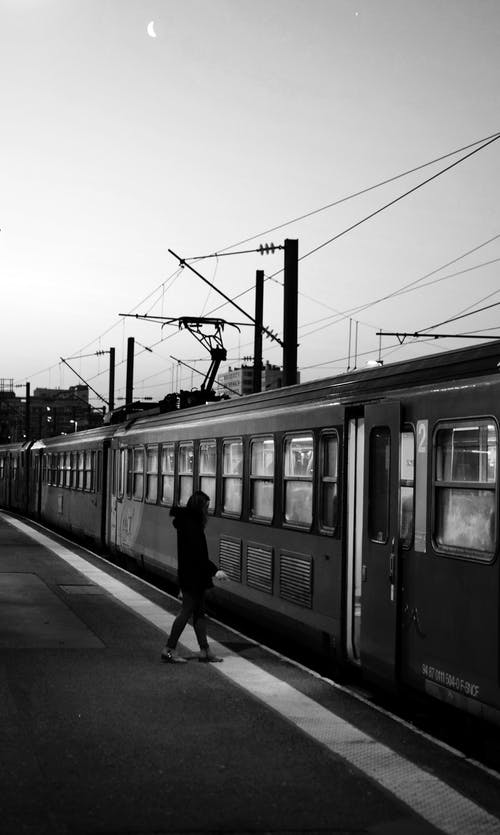站在火车旁边的人的单色照片 · 免费素材图片