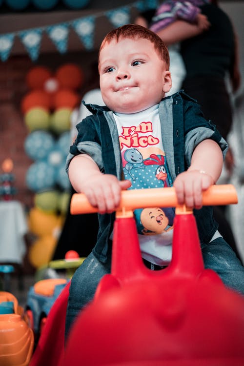 婴儿深蓝色外套，坐在红色的塑料椅子上 · 免费素材图片