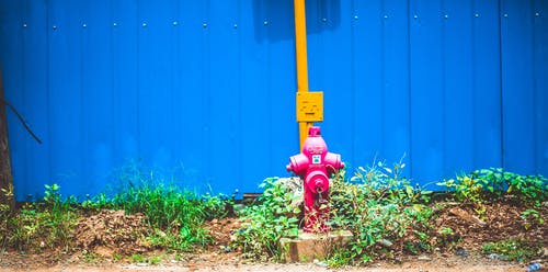 蓝篱笆后面的粉红色钢水泵 · 免费素材图片