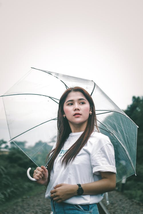 拿着伞的白色长袖衬衫的女人 · 免费素材图片
