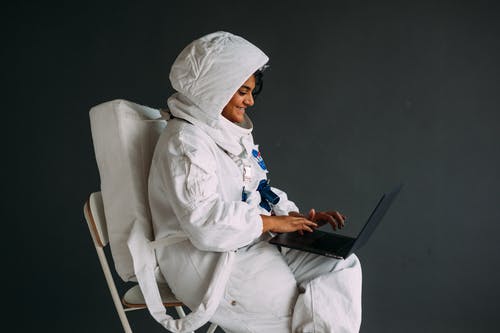 使用一台笔记本电脑的太空服的女人 · 免费素材图片