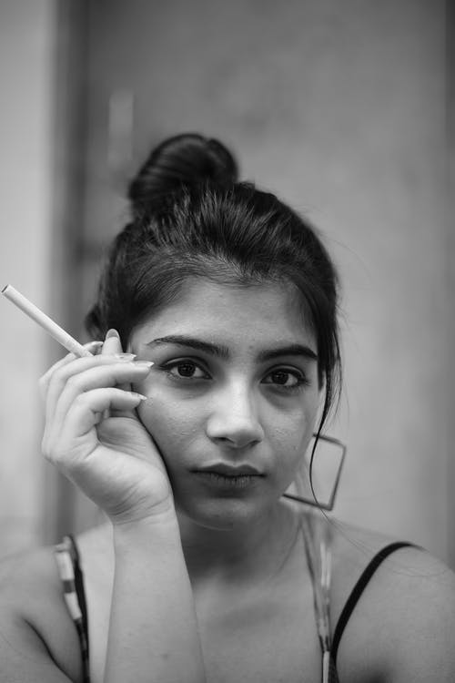 女人拿着香烟的灰度摄影 · 免费素材图片