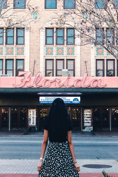 黑色衬衫站在棕色和白色大楼前的女人 · 免费素材图片