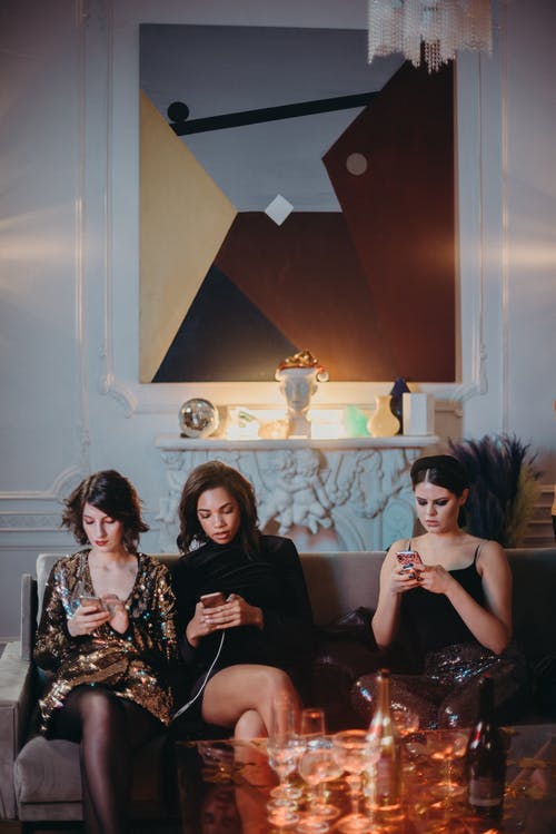 三名女子坐在沙发上使用智能手机 · 免费素材图片