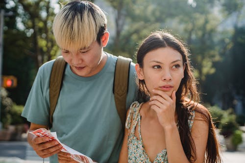 年轻多样的失落的夫妇在地图中找到路线 · 免费素材图片