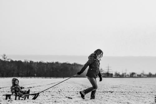 带婴儿的女人拉雪橇 · 免费素材图片