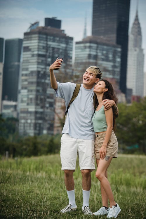 快乐的年轻多民族夫妇拥抱和采取自拍照在城市公园 · 免费素材图片