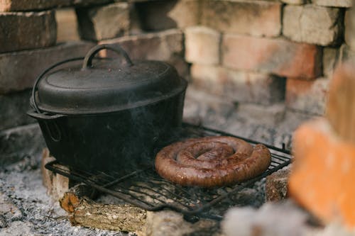 英尺长的香肠和黑色金属烤架上的黑色烹饪锅 · 免费素材图片