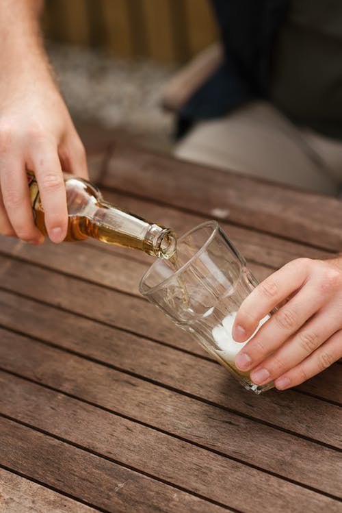 男子用发泡啤酒填充玻璃杯子 · 免费素材图片