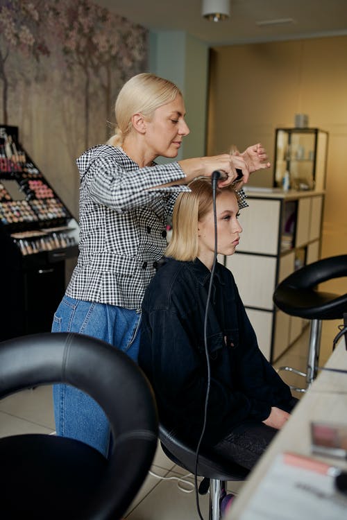 发型师用铁拉直女人的头发 · 免费素材图片