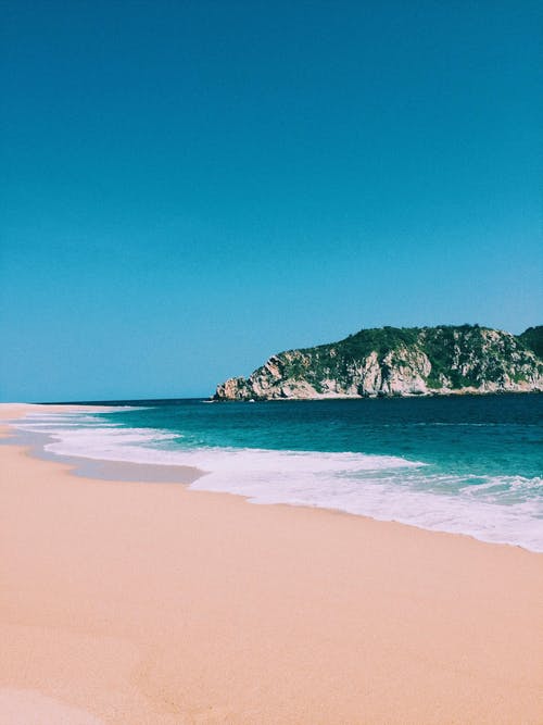 蓝天下的绿山附近的蓝色大海 · 免费素材图片