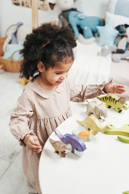 女孩玩木制的桌子上的白玩具的选择性焦点照片 · 免费素材图片