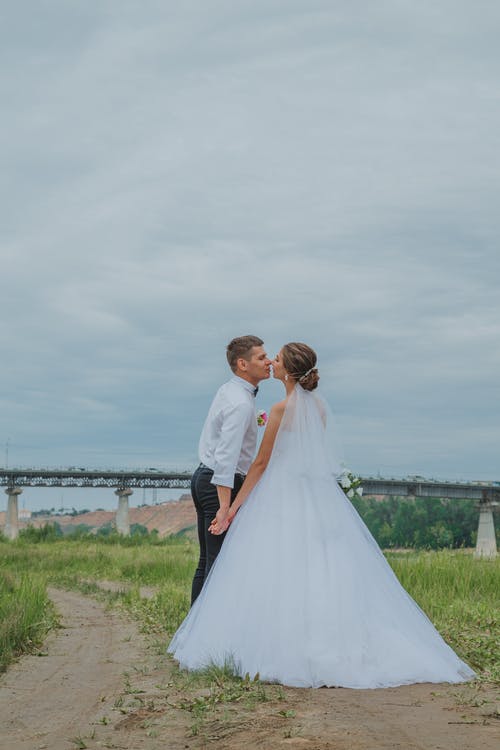 新娘和新郎站在绿色的田野 · 免费素材图片