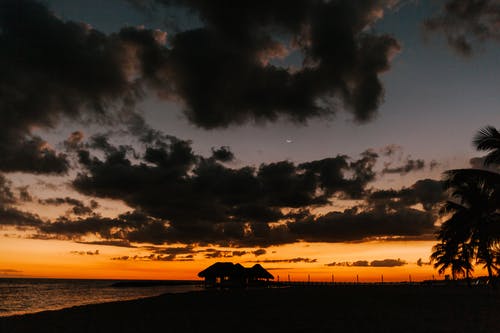 在日落时云下的稻草屋顶小屋 · 免费素材图片