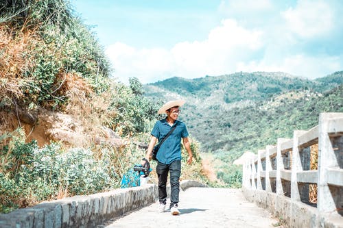 蓝色牛仔夹克和棕色的帽子，在灰色的混凝土桥上行走的人 · 免费素材图片